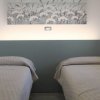 Due letti singoli con copriletti beige e quadro di fiori sopra.