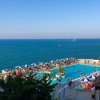 Piscina vista mare con ombrelloni blu e bianchi.