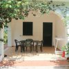 Terrazza con tavolo e sedie sotto una pergola di piante rampicanti.