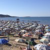 Spiaggia affollata con ombrelloni colorati e persone che nuotano nel mare.