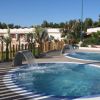 Due piscine circolari con cascate d'acqua in un giardino recintato da pali di legno.