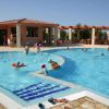Bambini che nuotano in una piscina all'aperto con un piccolo edificio sullo sfondo.