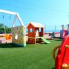 Parco giochi con casetta di legno e scivolo.