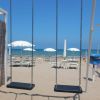 Altalene su una spiaggia con ombrelloni bianchi.