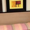 Interno di una camera con un letto a righe colorate e quadri astratti sul muro.