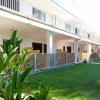 Un edificio bianco con balconi e un giardino verde in primo piano.