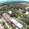 Veduta aerea di un grande complesso circondato da alberi e campi, con il mare all'orizzonte.